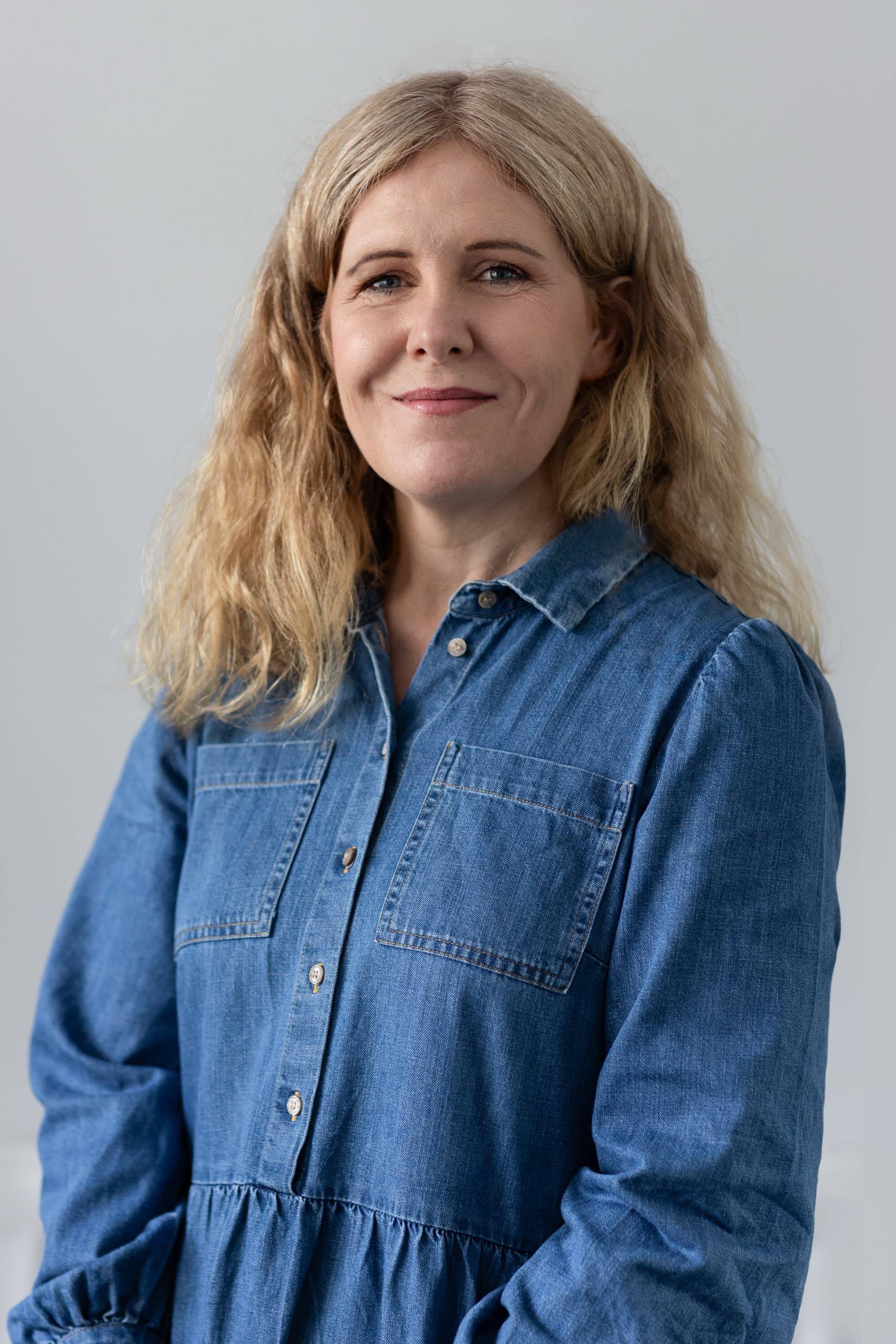Emma Gordon, founder and owner of Bydand Strategic Communications, wearing a blue denim dress against a neutral background